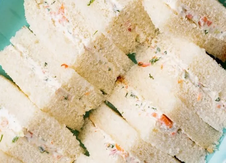 Veggie cream cheese finger sandwiches arranged on a platter for a party