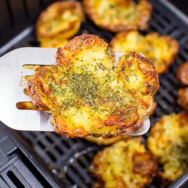 Crispy air fryer smashed potatoes garnished with herbs