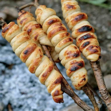 Homemade campfire bread cooking over an open flame