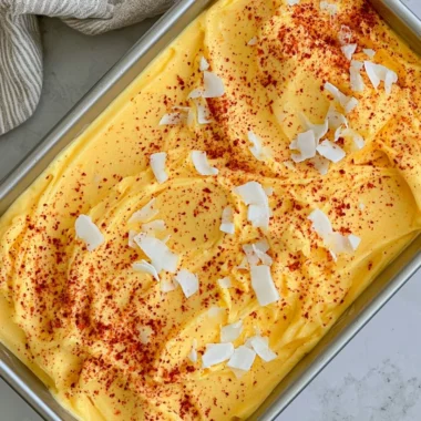 Bowl of vibrant chili lime mango sorbet garnished with lime slices