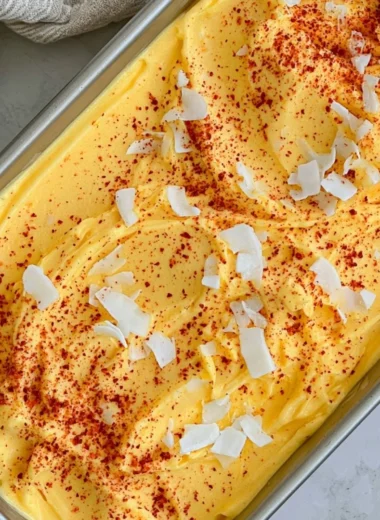 Bowl of vibrant chili lime mango sorbet garnished with lime slices