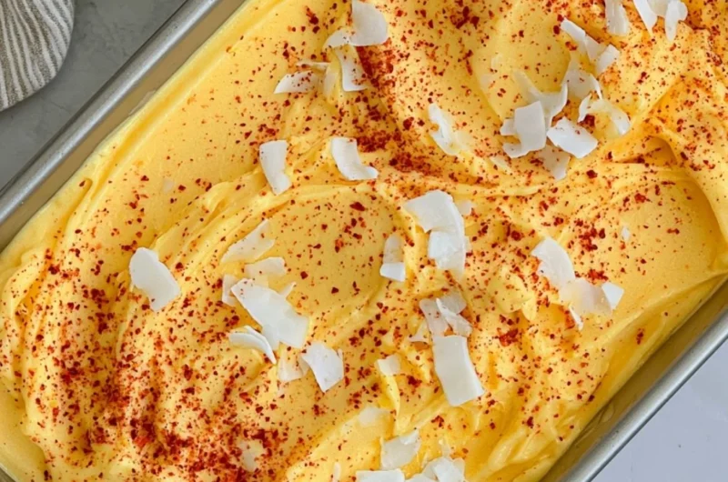 Bowl of vibrant chili lime mango sorbet garnished with lime slices