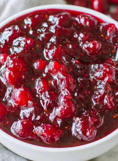 Homemade classic cranberry sauce in a serving bowl with fresh cranberries