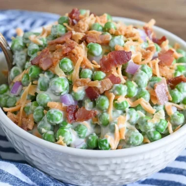 Bowl of classic pea salad with bacon, showcasing fresh peas and vibrant ingredients.