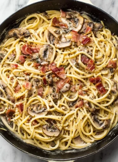 Bowl of creamy bacon mushroom pasta topped with herbs