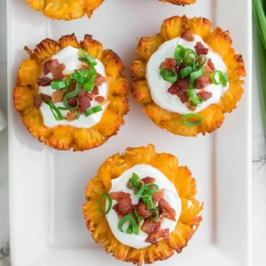 Plate of loaded tater tots appetizers topped with cheese, bacon, and green onions.