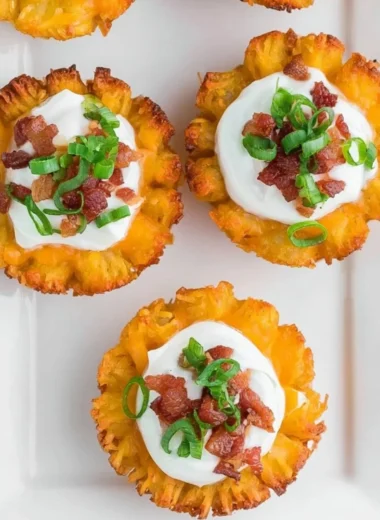 Plate of loaded tater tots appetizers topped with cheese, bacon, and green onions.