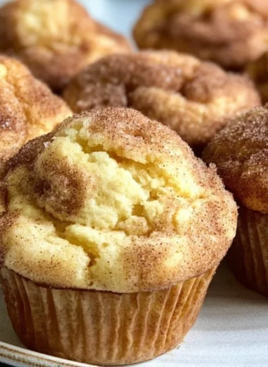 Freshly baked Snickerdoodle Muffins with cinnamon-sugar topping on a wooden table.