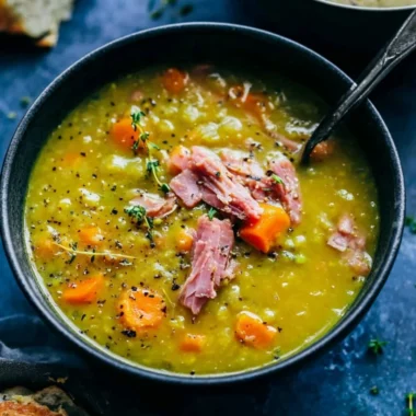 Bowl of hearty split pea soup garnished with herbs and bread.