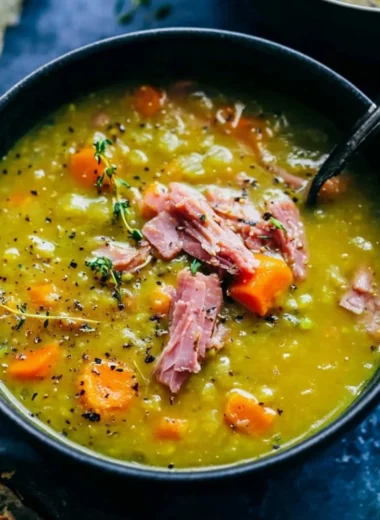 Bowl of hearty split pea soup garnished with herbs and bread.