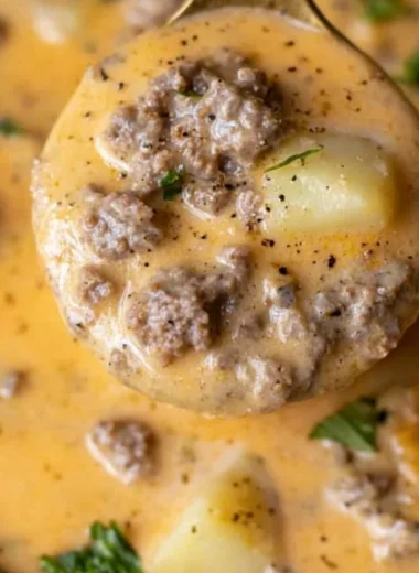 Bowl of cheesy beef and potato soup garnished with herbs