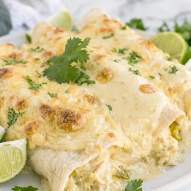 Delicious cozy creamy white chicken enchiladas topped with cheese and cilantro.
