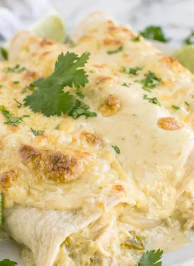 Delicious cozy creamy white chicken enchiladas topped with cheese and cilantro.