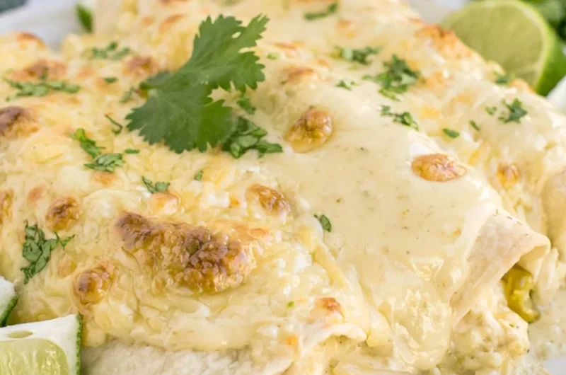 Delicious cozy creamy white chicken enchiladas topped with cheese and cilantro.