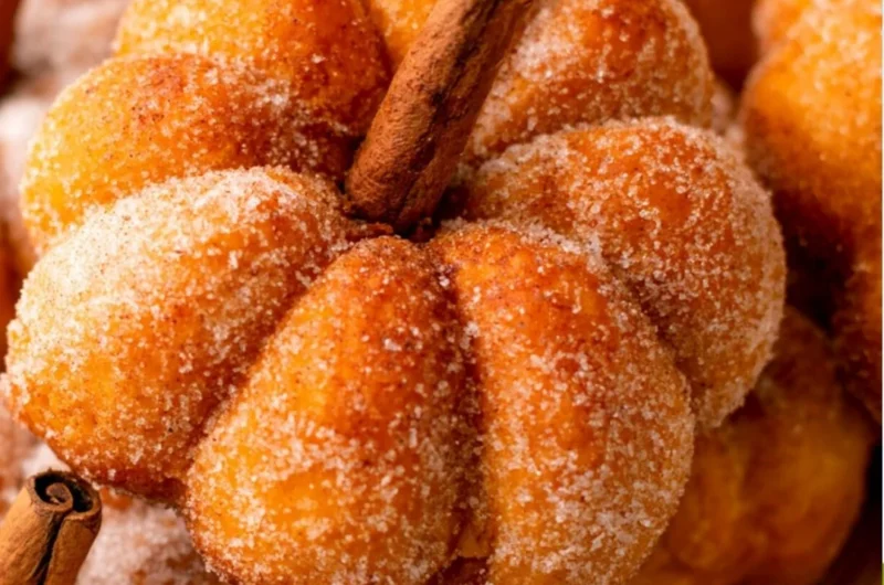 Cozy pumpkin donuts on a wooden table with autumn decorations