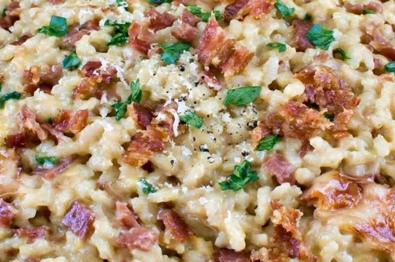 Creamy carbonara risotto garnished with herbs and cheese in a white bowl