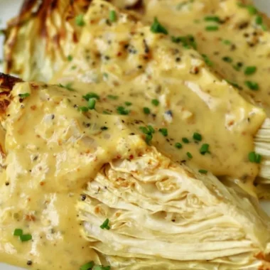 Roasted cabbage wedges served with onion-Dijon sauce on a plate