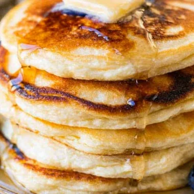 Fluffy ricotta pancakes topped with fresh berries and syrup on a plate.