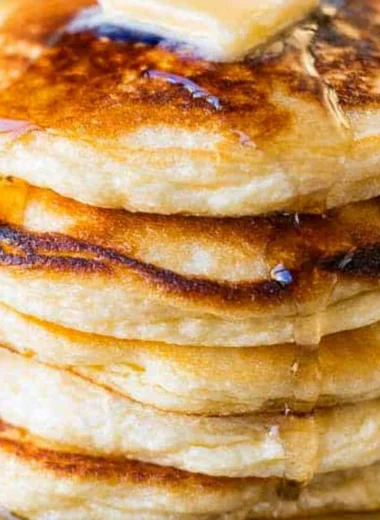 Fluffy ricotta pancakes topped with fresh berries and syrup on a plate.